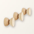 Three round geometric beech wood coat hooks with natural grain, on a warm-white backdrop