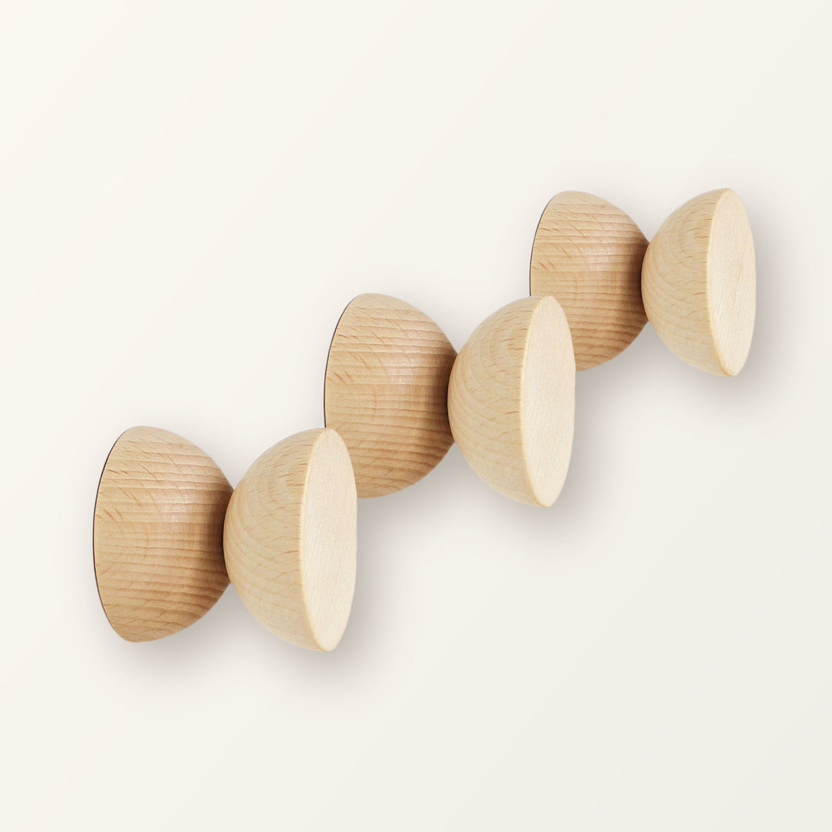 Three round geometric beech wood coat hooks with natural grain, on a warm-white backdrop