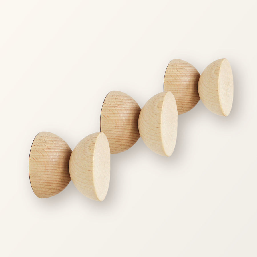 Three round geometric beech wood coat hooks with natural grain, on a warm-white backdrop