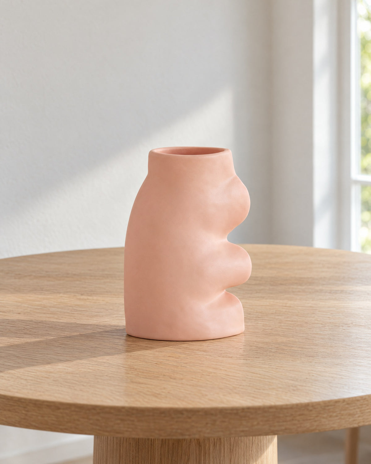 Fluxo large pink ceramic vase, empty, on a round light oak dining table in soft daylight