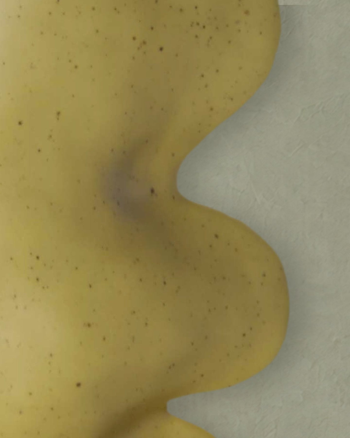 Close-up of the wavy side of the Fluxo large pistachio green vase in its speckled glaze