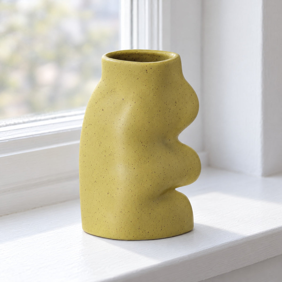 Fluxo large pistachio green ceramic vase, empty, on a white windowsill, seen from above to show its oval mouth