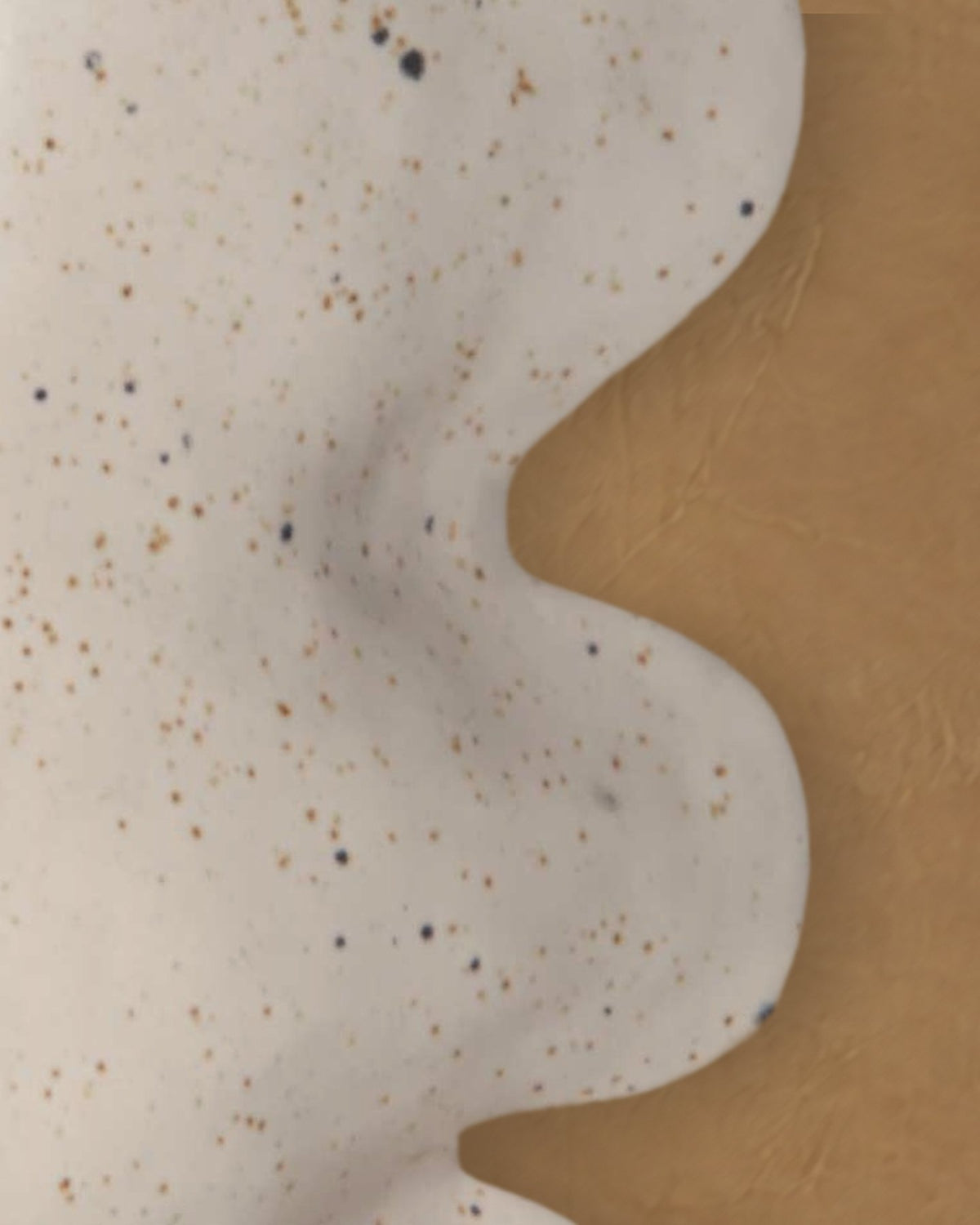 Close-up of the wavy side of the Fluxo large white vase in its speckled white glaze