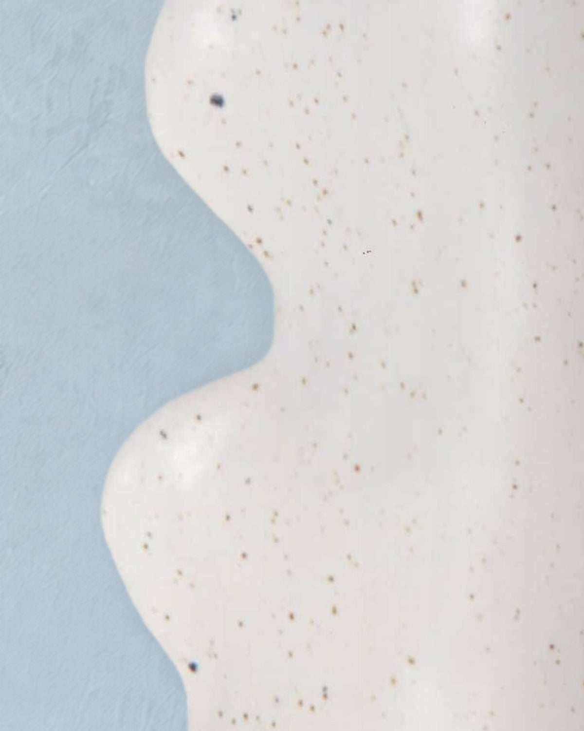 Close-up of the curving side of the Fluxo medium white vase in its speckled white glaze