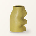 Fluxo large ceramic vase in pistachio green with a wavy side, on a plain warm-white backdrop