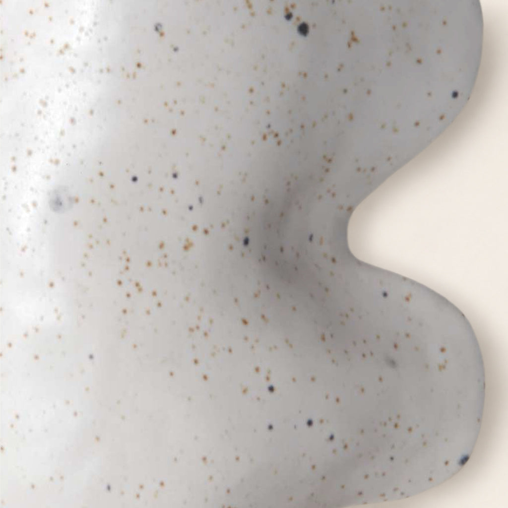 Close-up of the Fluxo white vase: matte white glaze with dark and brown speckles