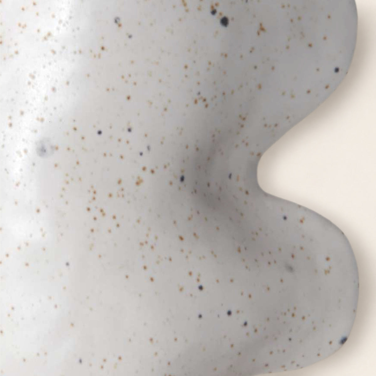 Close-up of the Fluxo white vase: matte white glaze with dark and brown speckles