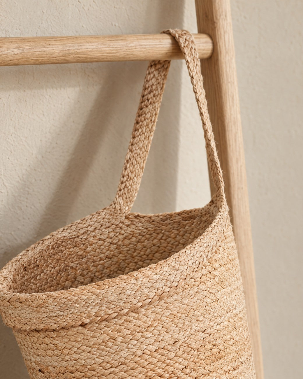 The Kata basket’s braided jute strap looped over the rung of an oak ladder