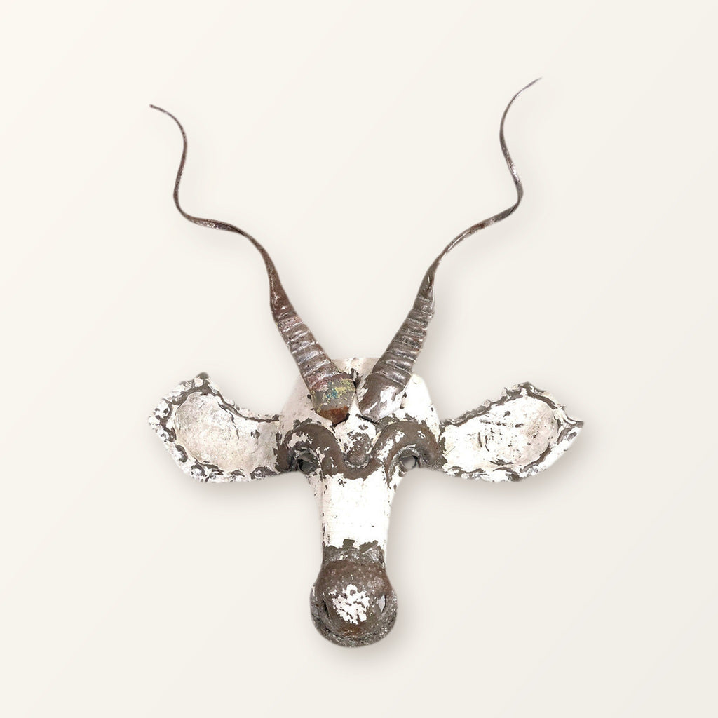Kudu antelope mask of recycled car tin with spiralling horns, white paint worn back to bare metal; colour varies