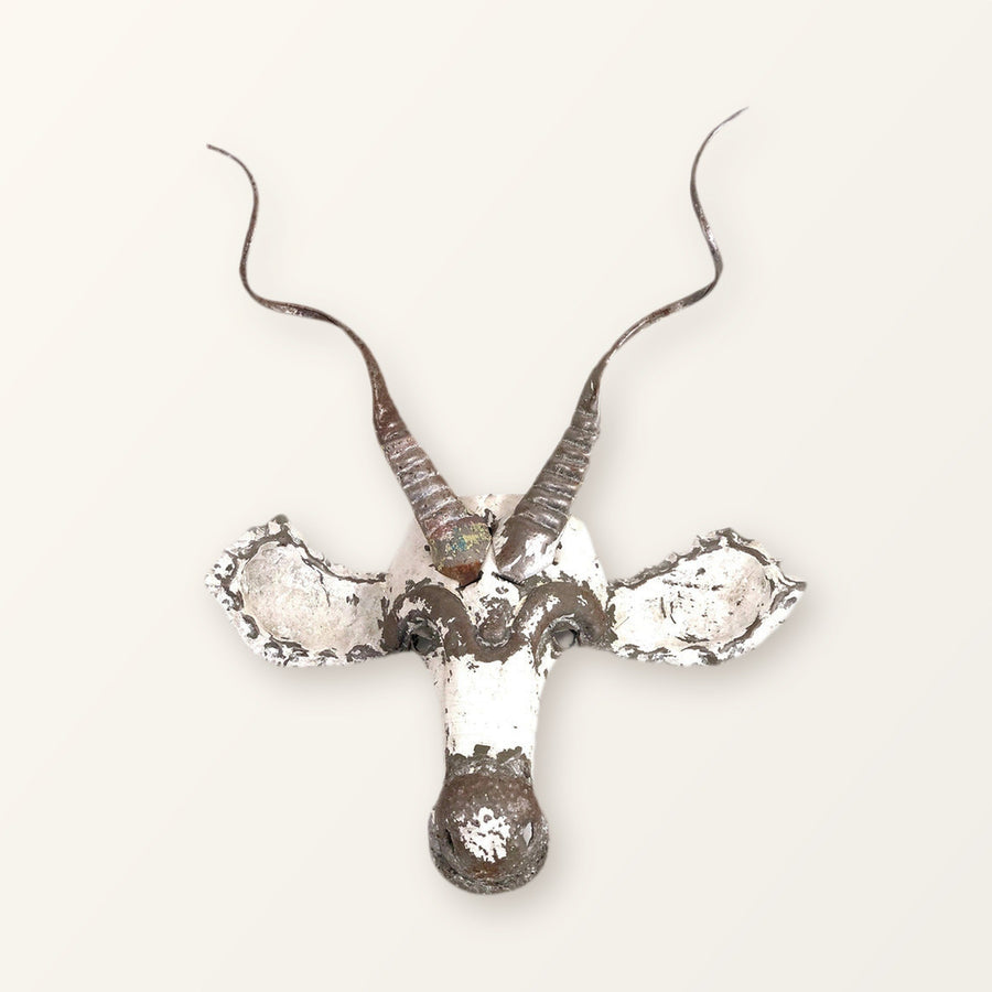 Kudu antelope mask of recycled car tin with spiralling horns, white paint worn back to bare metal; colour varies