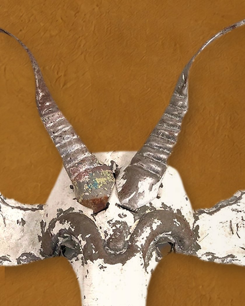 Close-up of the Kudu mask’s ridged spiral horns rising from the brow, worn white paint over metal