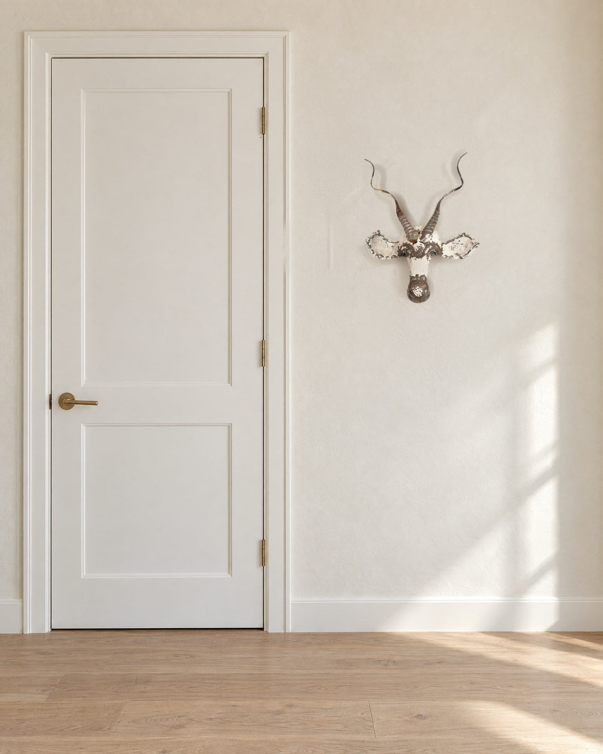 Kudu recycled metal wall mask, about 21 x 16 in, on a warm white wall beside a standard 80 in door