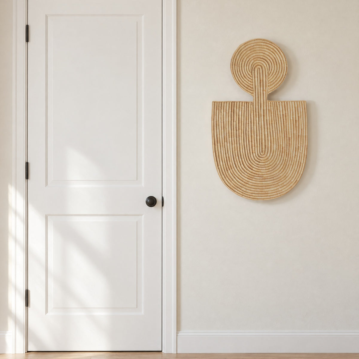 Abstract Wall Mask 1 hung on an off-white entry wall beside a white panel door