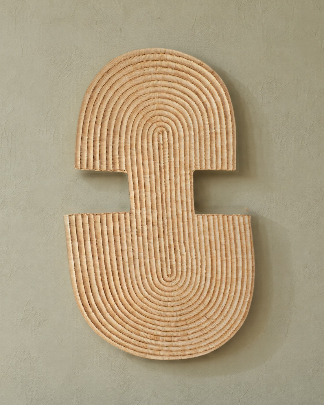 Abstract Wall Mask 2 in natural woven fibre on a pale sage plaster wall