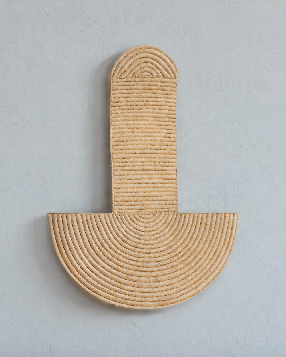 Abstract Wall Mask 3 in natural woven fiber on a pale blue-grey plaster wall