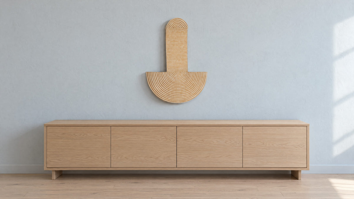 Abstract Wall Mask 3 hung on a pale blue-grey plaster wall above a long low oak sideboard, in soft window light