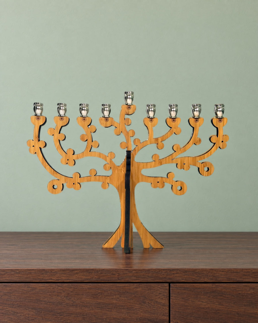 Tree of Life bamboo menorah on a walnut sideboard against a soft sage-green wall