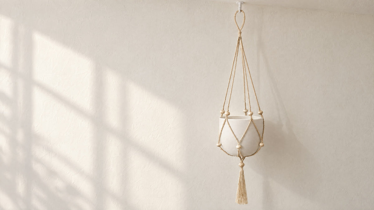 Nadu jute macrame plant hanger on a small white ceiling hook in front of a limewash wall, holding a plain white pot (pot and hook not included)