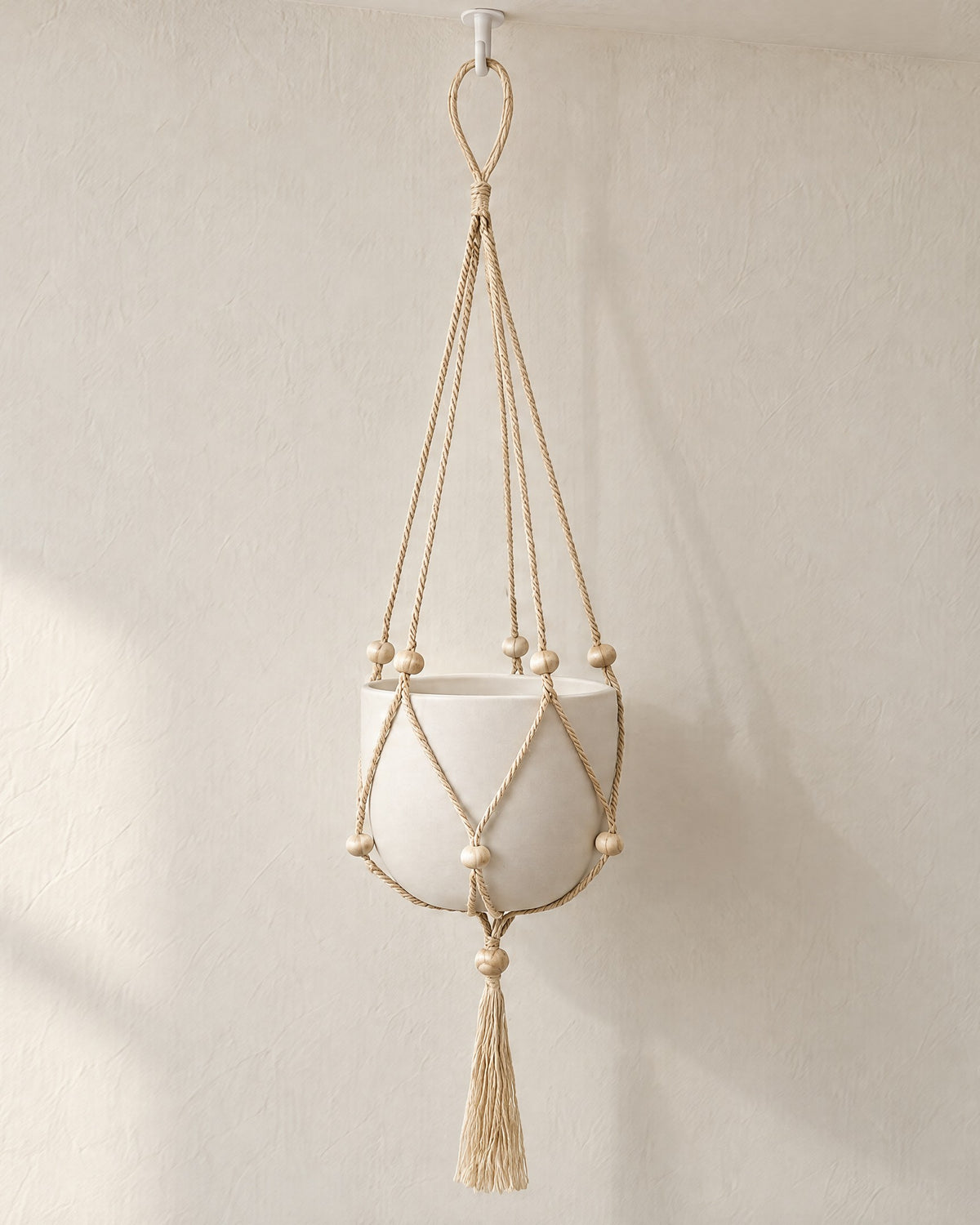 Nadu jute plant hanger on a ceiling hook in soft window light, shown holding a plain white pot (pot and hook not included)