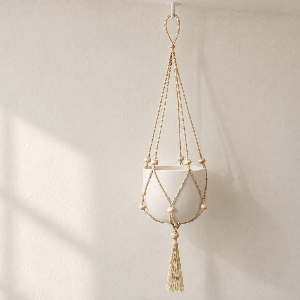Nadu jute plant hanger on a ceiling hook in soft window light, shown holding a plain white pot (pot and hook not included)
