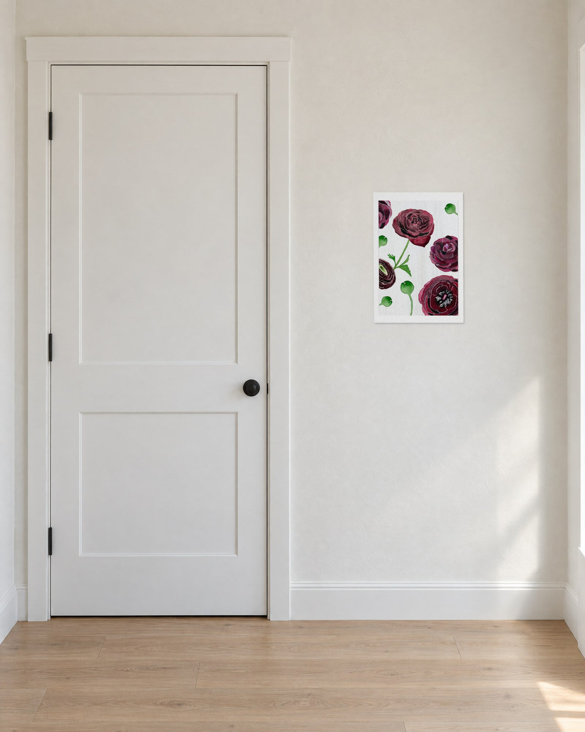 Unframed Black Ranunculus on Snow print, 13 x 19 in size, on a warm white entry wall beside a white door