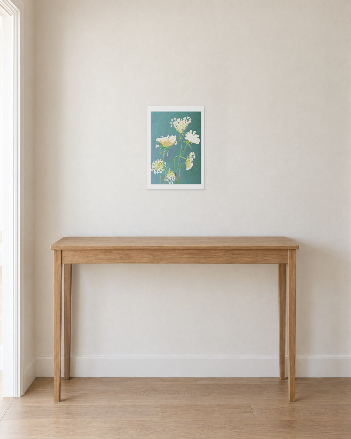 Unframed Queen Anne's Lace on Teal print, 13 x 19 in size, on a warm white hallway wall above a slim oak console