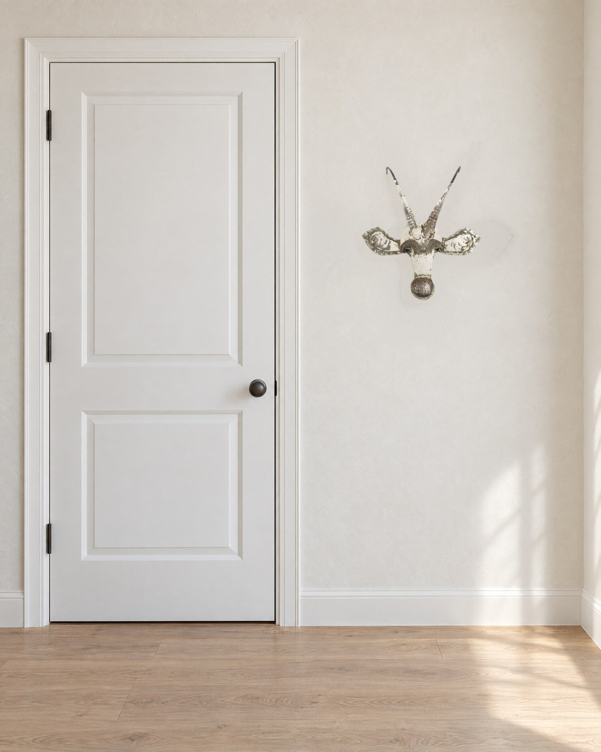 Sable recycled metal wall mask, 17 in wide, on a warm white wall beside a standard 80 in door