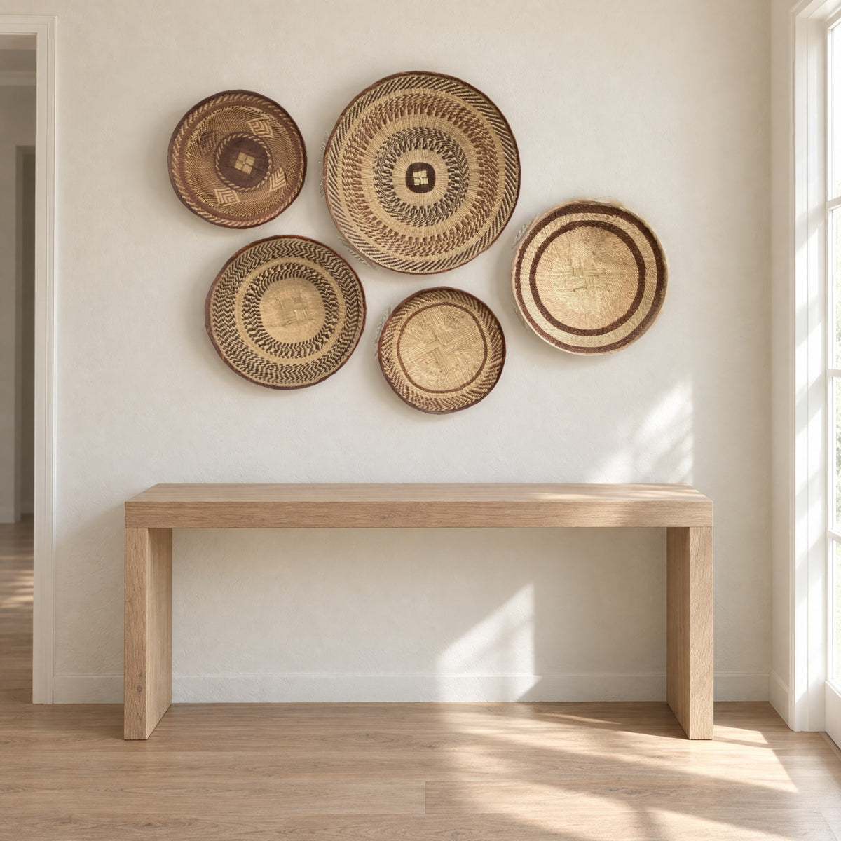 Five Tonga baskets hung on a warm white hallway wall above a slim oak console table