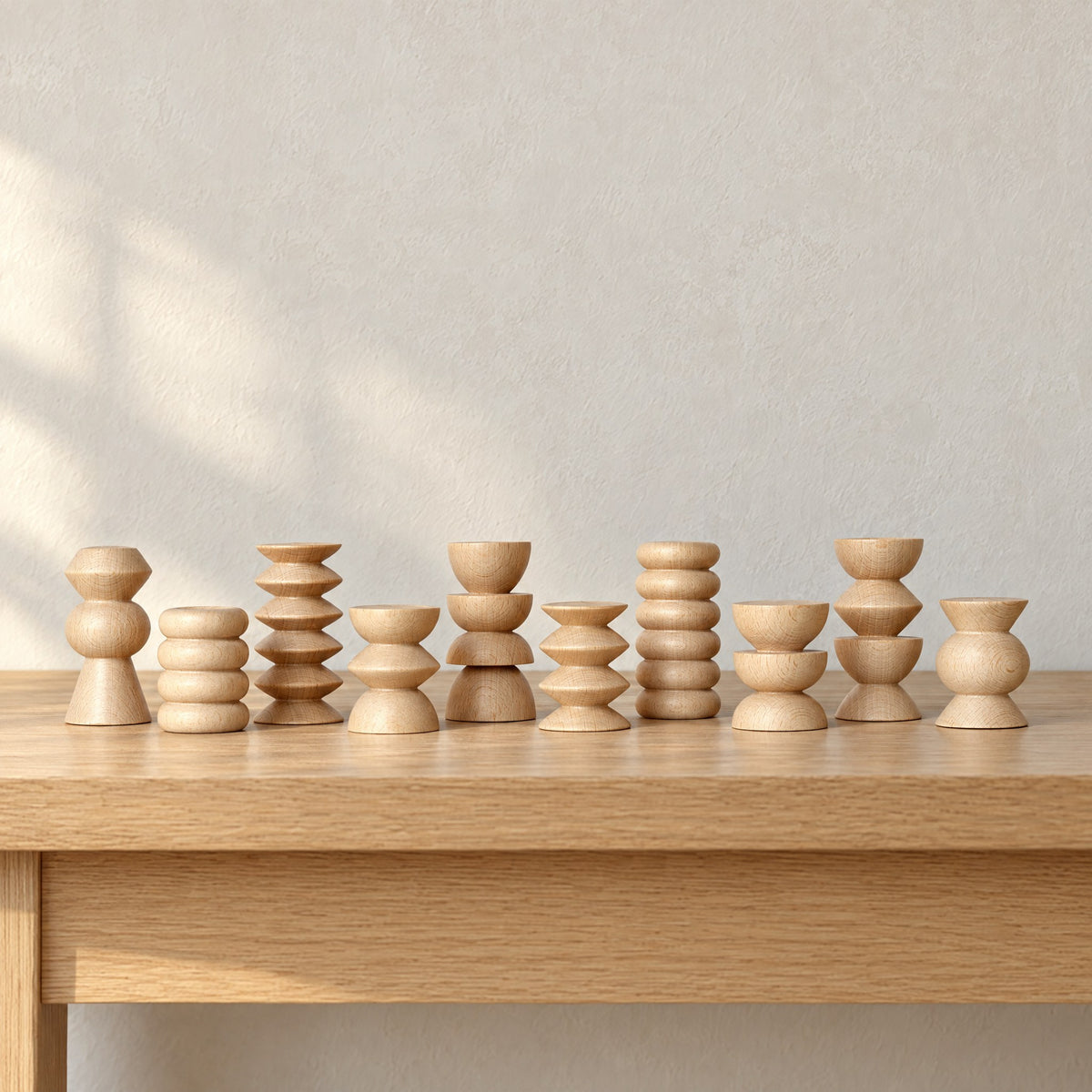 Ten wooden Totem stands in a row on a light oak console table against a pale wall