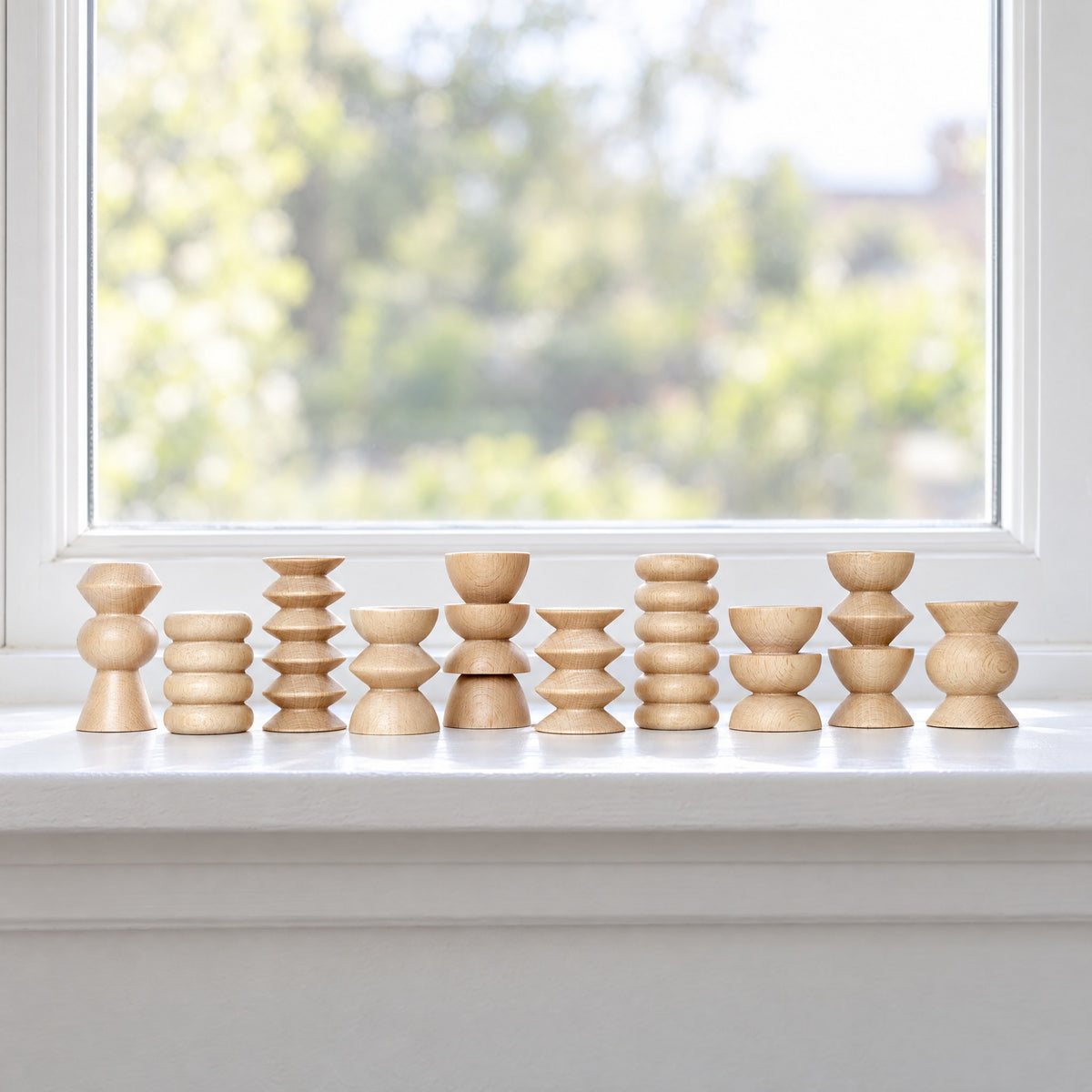 Ten wooden Totem stands in a row on a white windowsill in daylight
